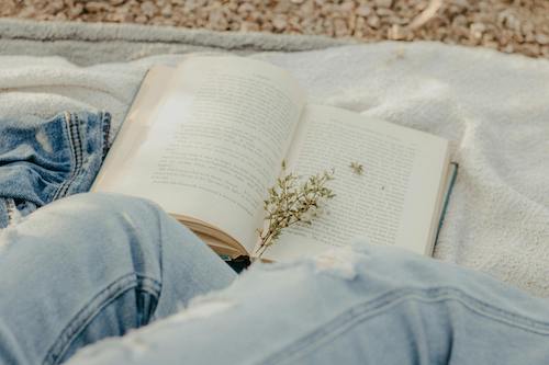 Person wearing jeans reading a book
